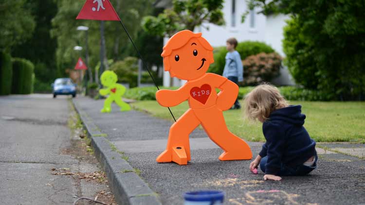 Kind malt mit Straßenkreide vor einem Sicherheitsschild von betzold.de