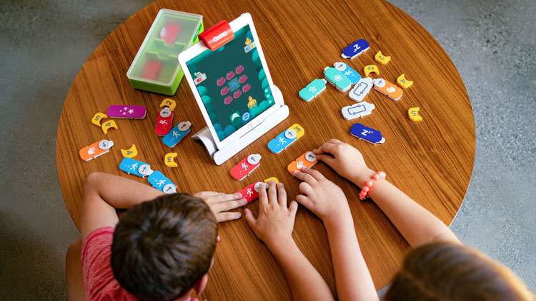 Kinder, die auf einem Tisch ein digitales Lernspiel von Osmo spielen.