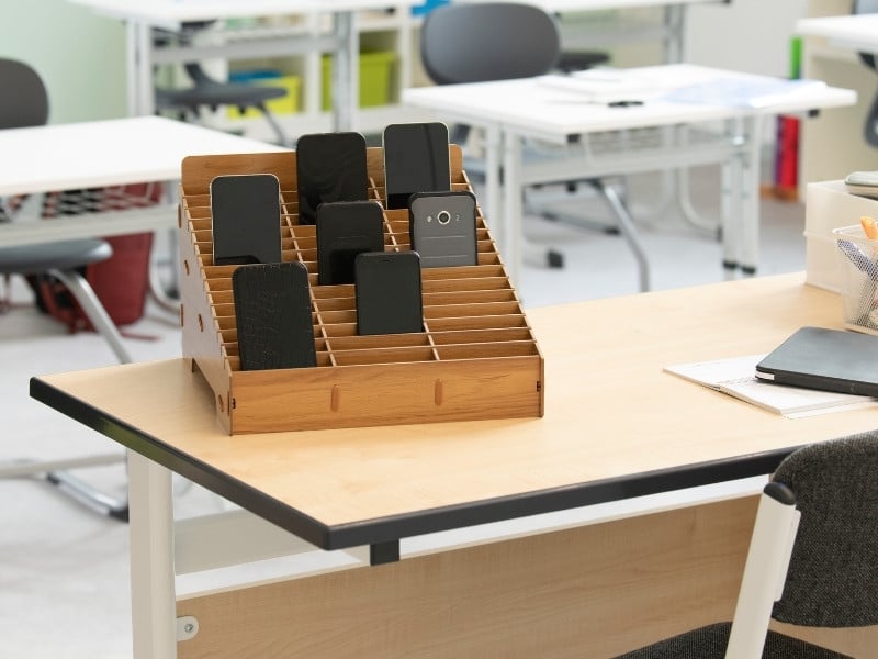 Konzentration Handyparkplatz Handygarage aus Holz mit Fächern für Smartphones auf einem Lehrerpult