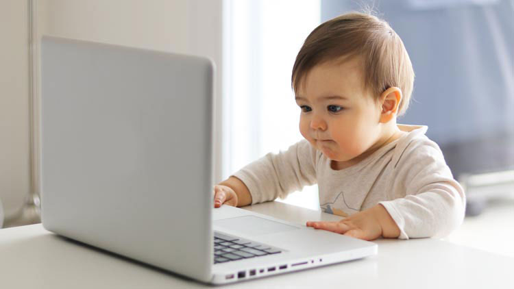 Kleinkind sitzt konzentriert an einem Laptop
