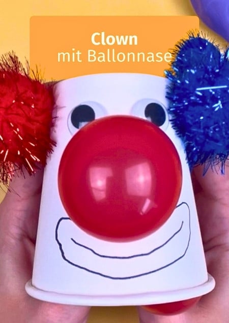 Clown gebastelt aus einem Pappbecher, dem eine Nase aus einem roten Luftballon wächst.