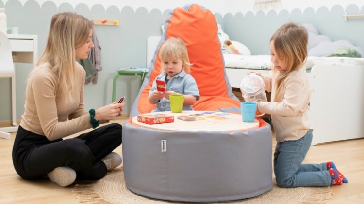 Erzieherin sitzt mit 2 Kindern an einem Tisch