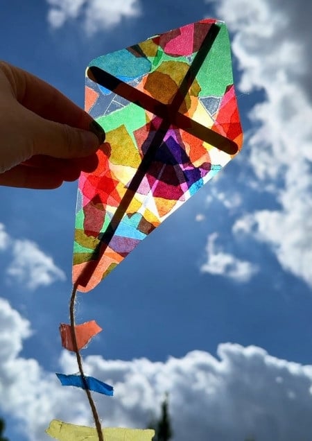 Kleiner Drachen aus Transparentpapier an einem Fenster, durch das die Sonne scheint