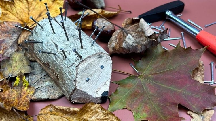 Holzstämmchen mit Nägeln verziert, um einen Igel darzustellen