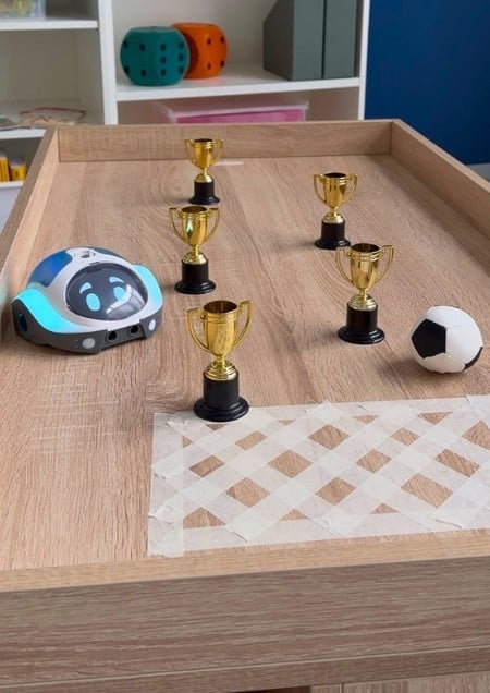 Loti-Bot auf dem Spielfeld mit Pokalen und Ball