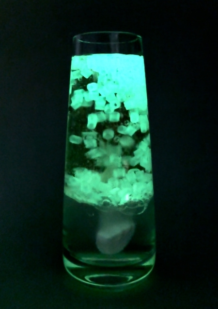Nachtleuchtende Wasserperlen, die durcheinander wirbeln, in einem Glas .