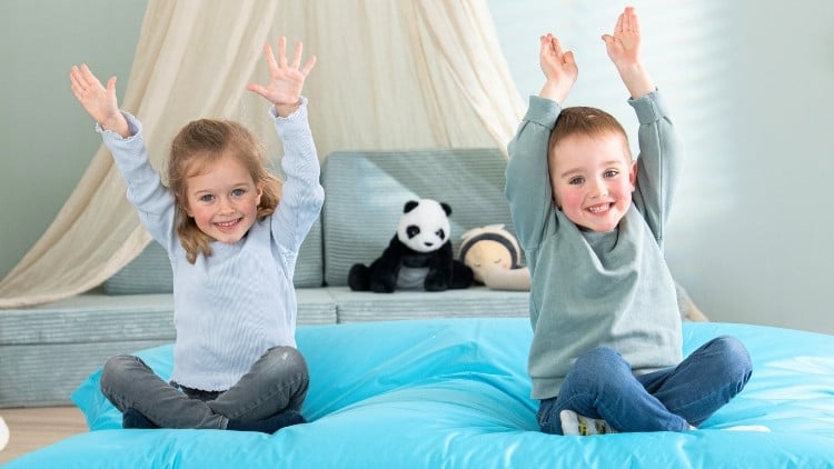 2 Kinder sitzen auf einem blauen Sitzsack von Betzold.