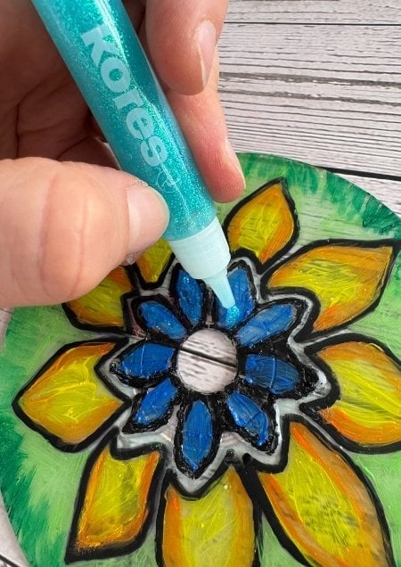 Eine alte CD, die mit Glitzerkleber und Acryfarbe gestaltet wurde.