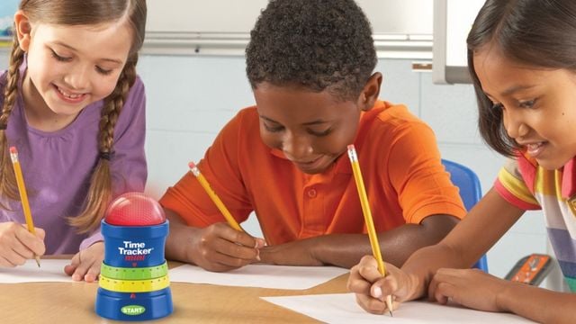 Kinder sitzen im Unterricht am Tisch und schreiben