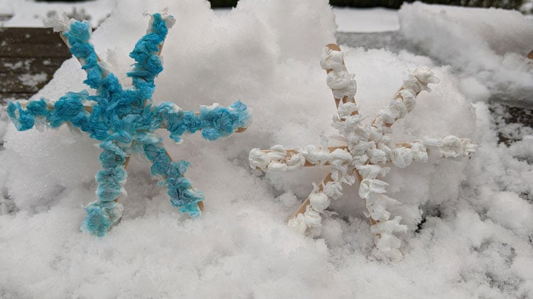 Schneeflocken aus Holzstäbchen, beklebt mit Taschentüchern.