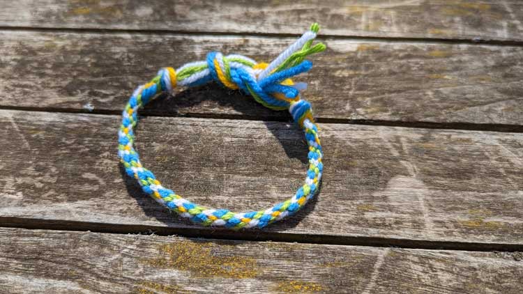 Mit einem Pappkreis lässt sich ganz einfach mit ein wenig Wolle ein Armband knüpfen.