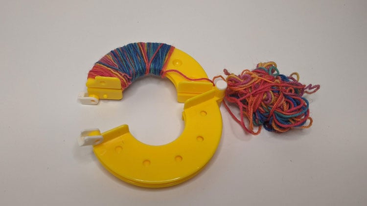 Pompon-Schablone mit Wolle aus dem Betzold Online-Shop umwickelt.