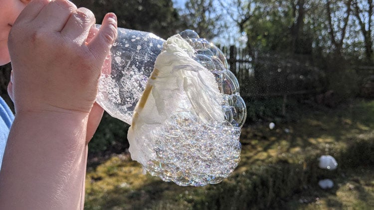 Seifenblasen mit einer Plastikflasche und einem Stück Stoff pusten.