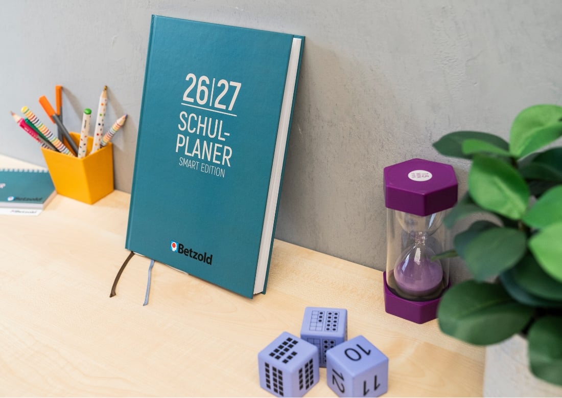 Smartplaner mit grünem Cover auf Tisch und gegen eine Wand gelehnt