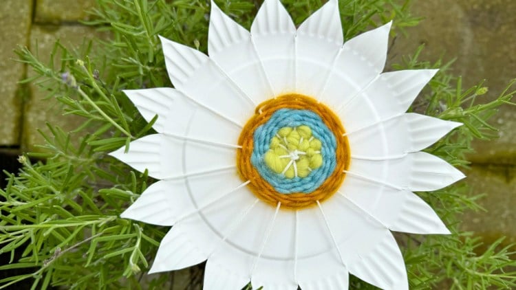 Der fertig bewebte Pappteller in Blumenform.