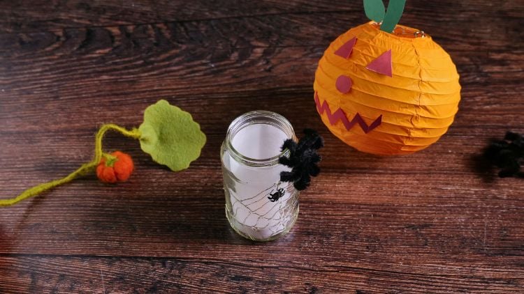 Mit einem Windlicht aus Glas, Bastelkleber und weißem Transparentpapier entsteht ganz einfach ein Halloween-Windlicht mit Spinnennetz.