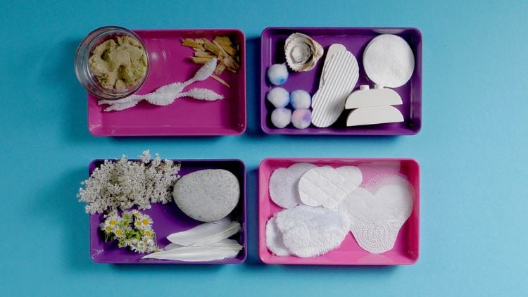 Unterschiedliche Materialien werden im Kindergarten auf einem Aktionstablett zur Verfügung gestellt, um eine Collage zu erstellen.