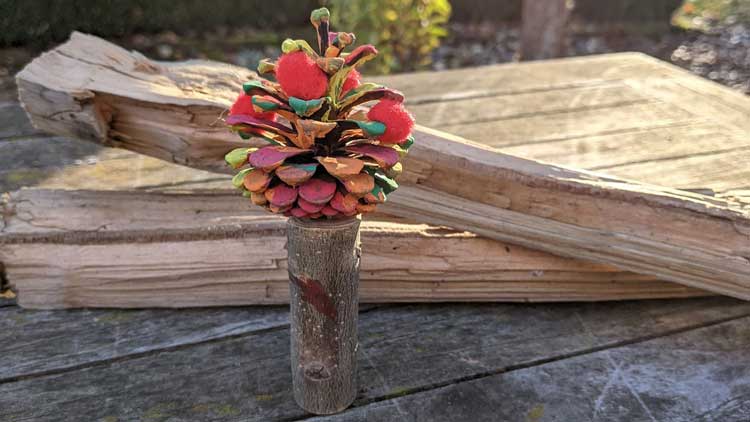 Mit einem Holzstämmchen aus dem Betzold Online Shop entsteht mit einem Kieferzapfen und Fingerfarbe ein herbstlicher Baum.