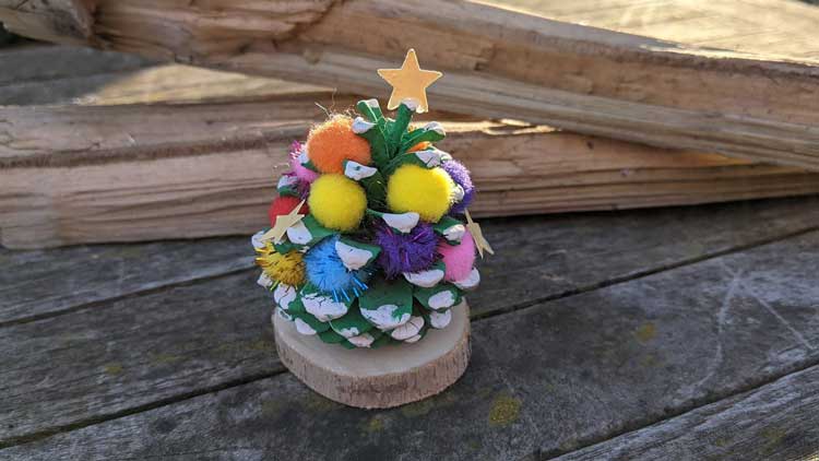 Einen einfachen Weihnachtsbaum können schon Kindergartenkinder mit Kieferzapfen, Fingerfarbe und Pompons herstellen.