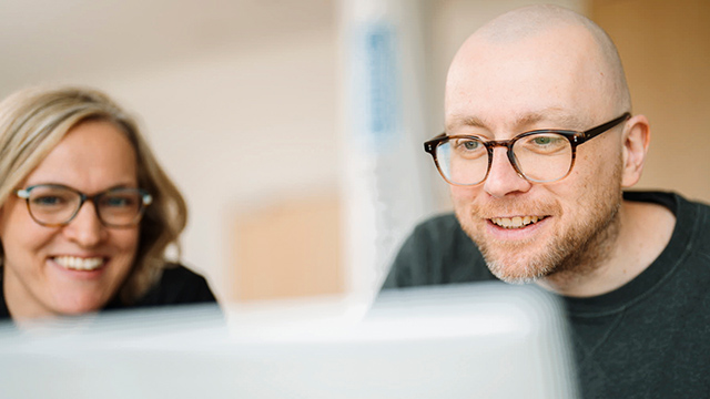 Personen informieren sich über Förderprogramme am Laptop