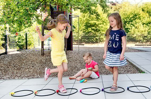 Kinder spielen Hüpfspiel im Garten