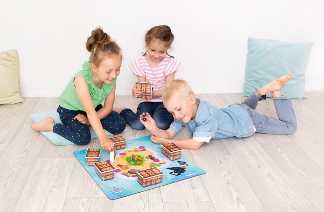 Kinder sitzen auf dem Boden und spielen ein Brettspiel