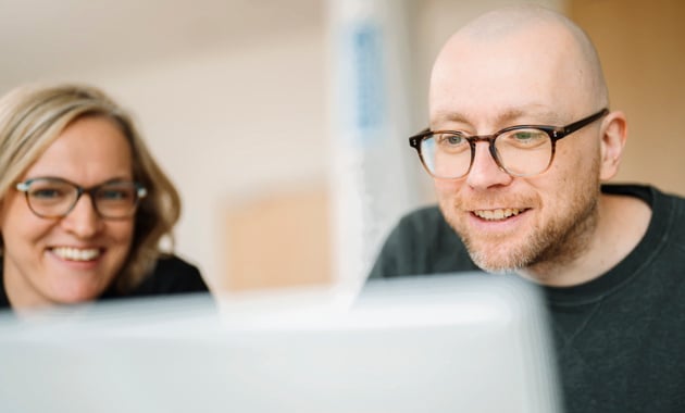 Personen informieren sich über Förderprogramme am Laptop