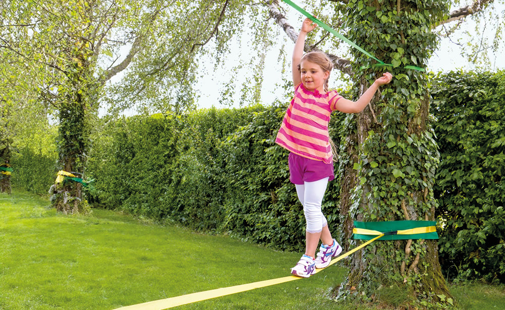 Mädchen balanciert auf Slackline