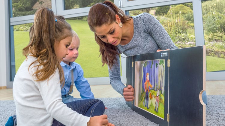 Erzieherin erzählt Kindern eine Geschichte mit dem Kamishibai