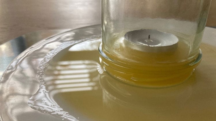 Kerze unter einem Glas mit gefärbtem Wasser