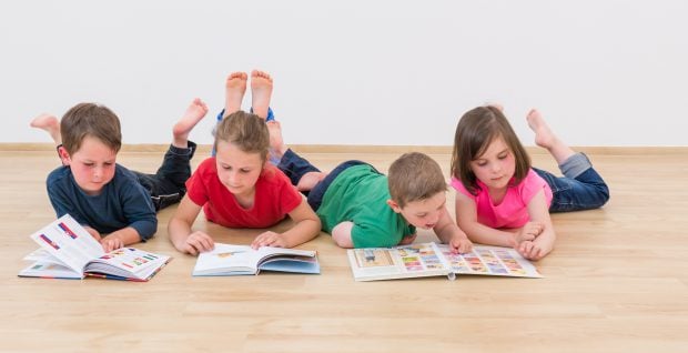 Kinder lesen auf Boden liegend