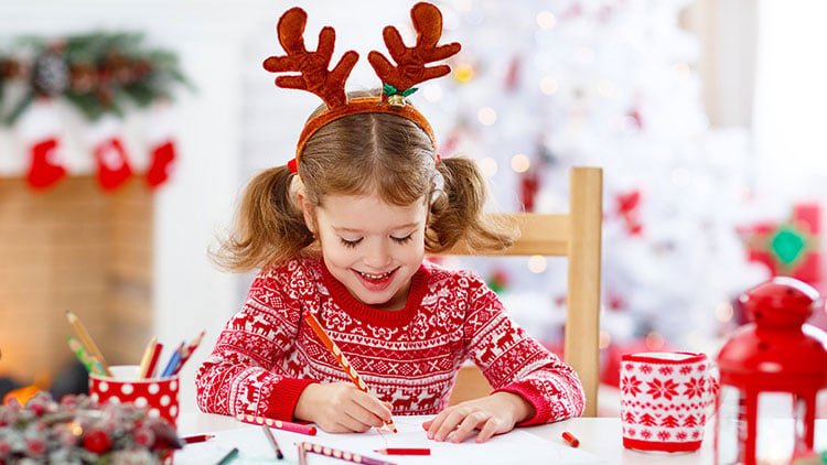 Kind in weihnachtlicher Kleidung beim Malen